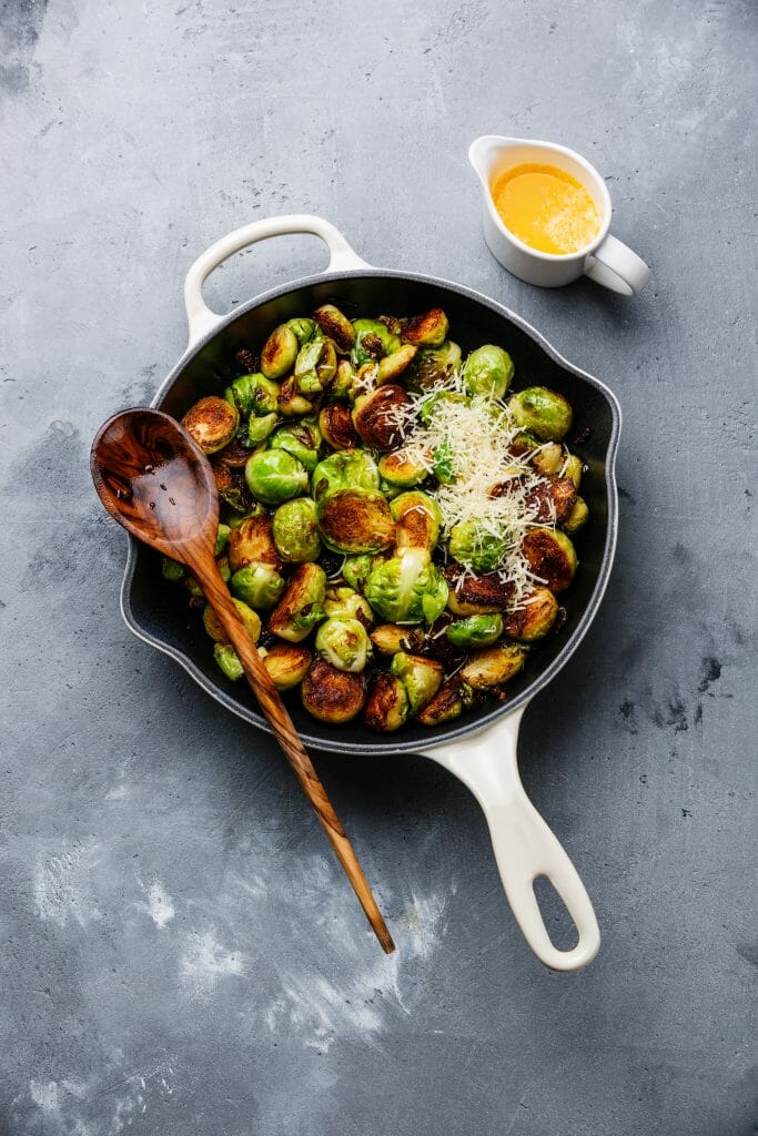 fried Brussels sprouts with parmesan cheese in frying pan on concrete background