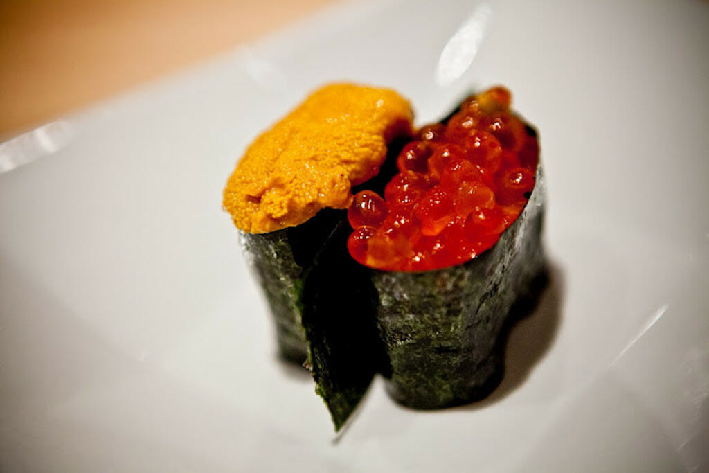 Two different pieces of sushi one with urchin and the other with fish eggs