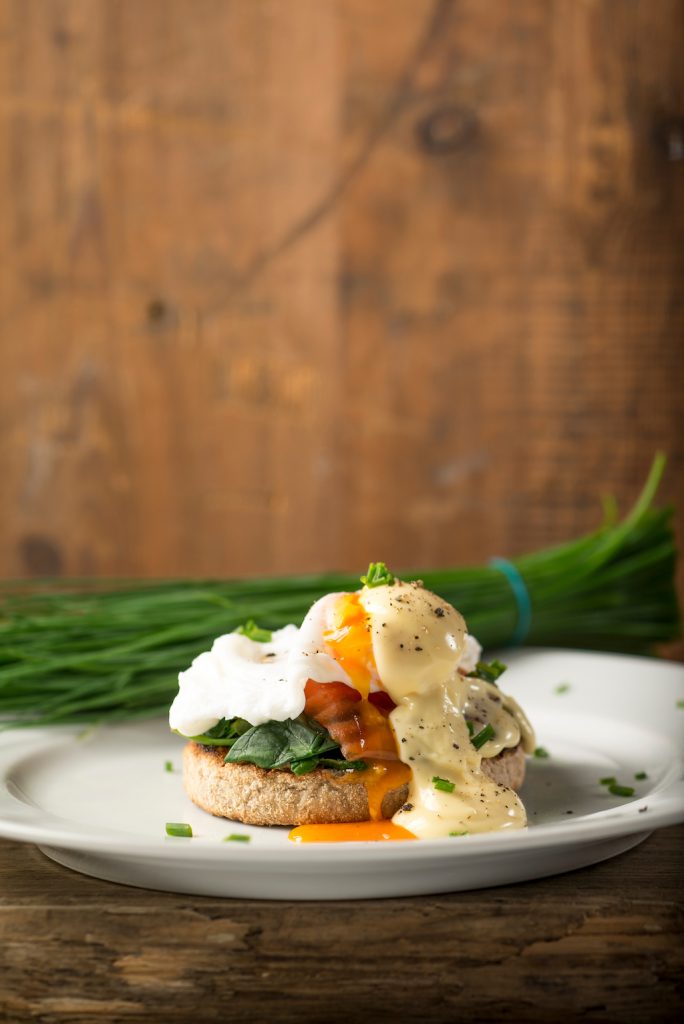 Smoked Salmon, poached egg and spinach on a toasted English Muffin with herbs in the background