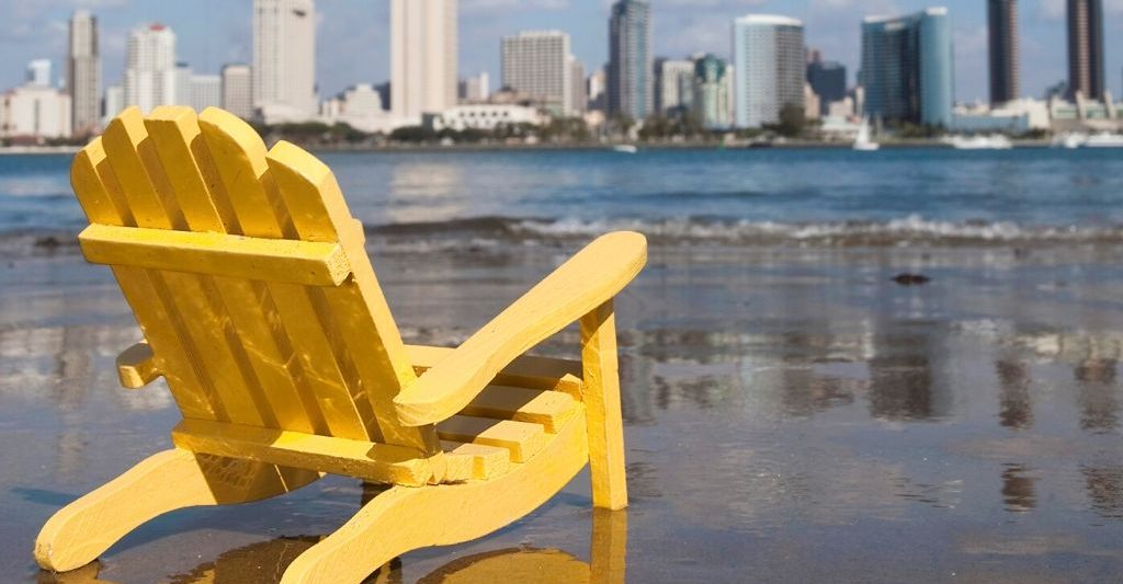 San Diego Staycation - Yellow beach chair on the beach in Coronado with the San Diego Skyline in the background
