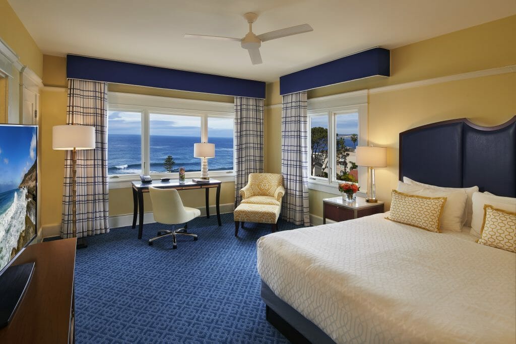 Luxurious hotel room with bed, and two windows looking out over the pacific ocean