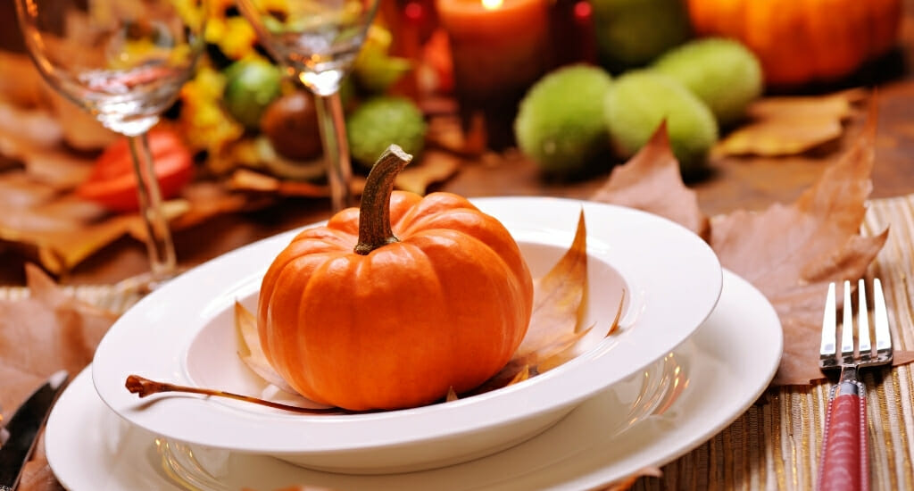Decorated table for thanksgiving with white plates and pumpkin decor
