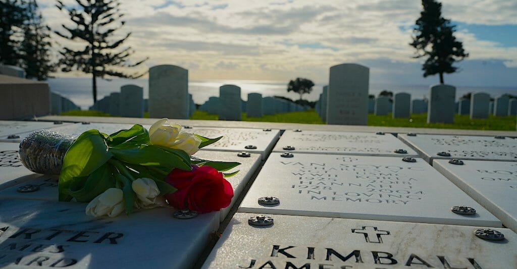 A bouquet of flowers laying on a white marble graveside plate with names inscribed at Fort Rosecrans National Military Cemetery San Diego