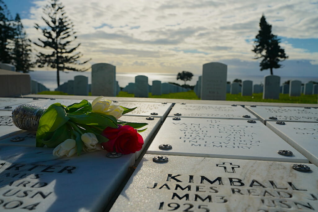 A bouquet of flowers laying on a white marble graveside plate with names inscribed at Fort Rosecrans National Military Cemetery San Diego
