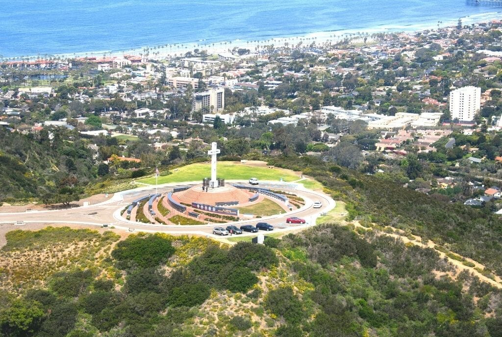 Aerial view fo white cross on top of Mt Soledad National Veterans Memorial San Diego with the ocean and the houses of La Jolla  in the background 