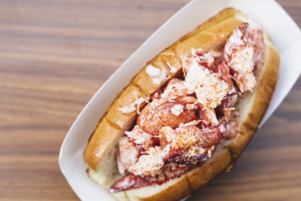 Close up of Wicked Maine Lobster Roll on a wood surface- Photo by Diana Rose Photography
