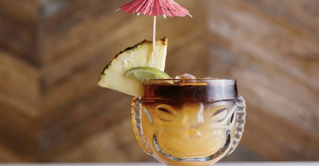 Mai Tai cocktail in a Tiki-inspired glass with slice of pineapple and pink umbrella