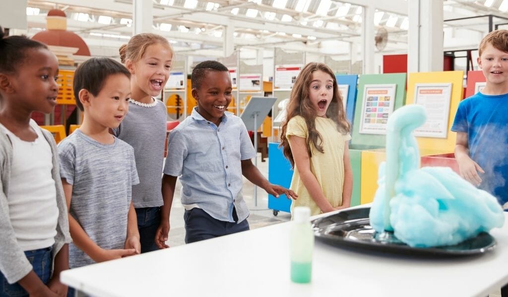 Children standing around a table watching a science experiment