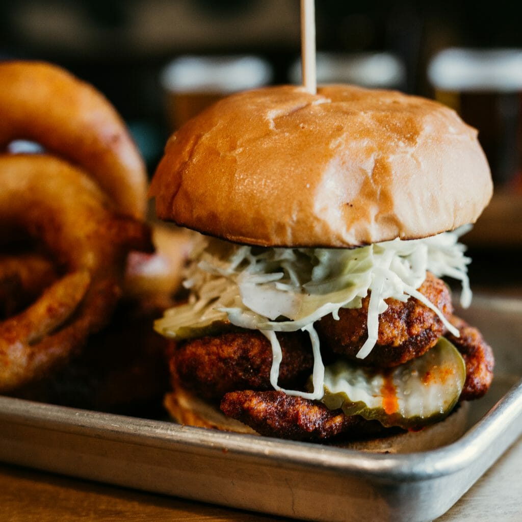 closeup shot of a burger and onion rings on a metal tray