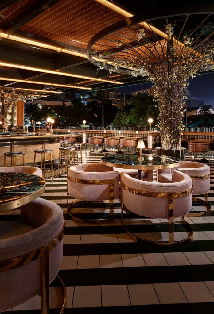 Stunning rooftop bar at Born and Raised San Diego with plush round pink chairs, black and white tile floor,