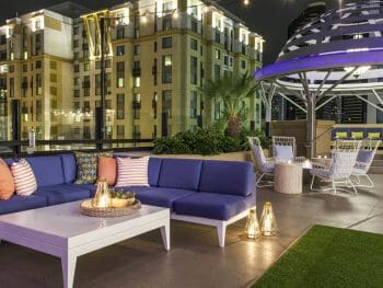 Rooftop bar at the Kimpton Solamar in San Diego with white outdoor couches with blue cushions on green fake grass