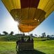 yellow hot air balloon flying over a golf course on a sunny day