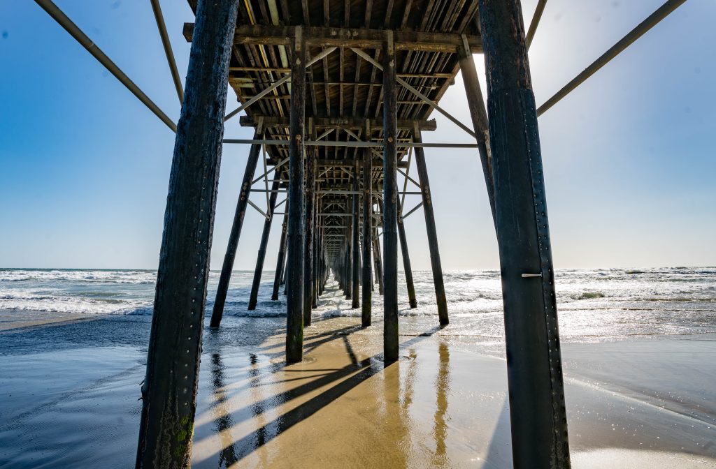 Photo of wooden beams at Oceanside pier photographed from the beach