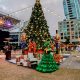 Christmas tree with lots of big presents and woman dressed in green dress at Petco Park Holiday Market San Diego