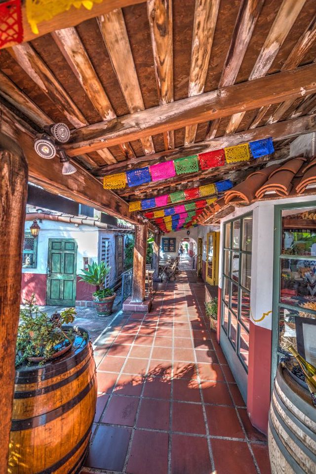 Storefronts with terracotta tile walkway, wood covered path and colorful paper garlands. Old Town, San Diego. NCTD coaster train stop.