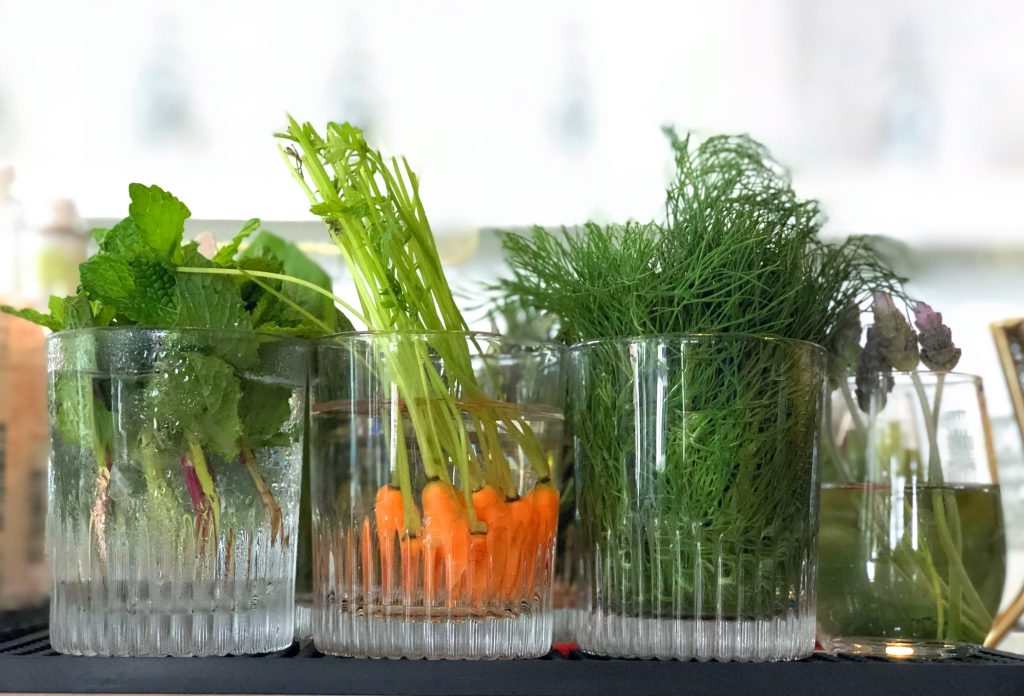 crystal glasses with cocktail decor and herbs, including mint, baby carrots, dill at You&Yours Distillery San Diego