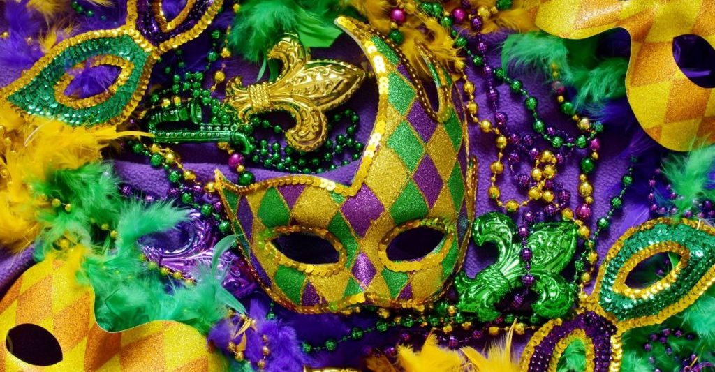 gold, purple, and green colored mardi gras mask, beads and feathers