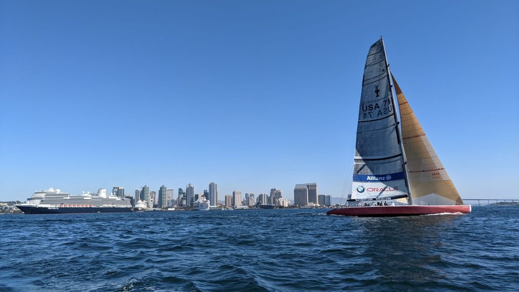 Sailboat sailing on San Diego Bay with blue sail in front of San Diego Skyline 