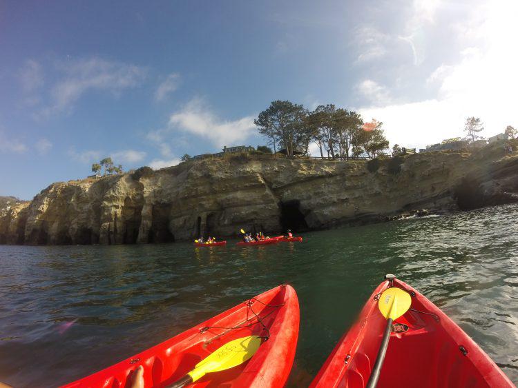 tip of two red kayaks in the forground and the la jolla caves in the background