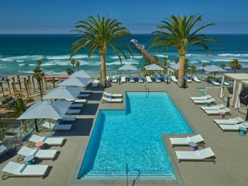 view over rooftop hotel pool at the Mission Resort Oceanside Hotels with lounge chairs with the pacific ocean in the background