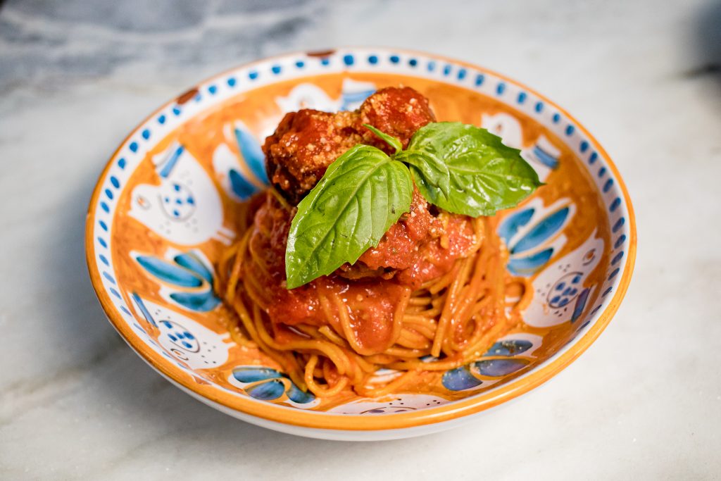 Spaghetti with tomato sauce, basil leaves on a colorful plate