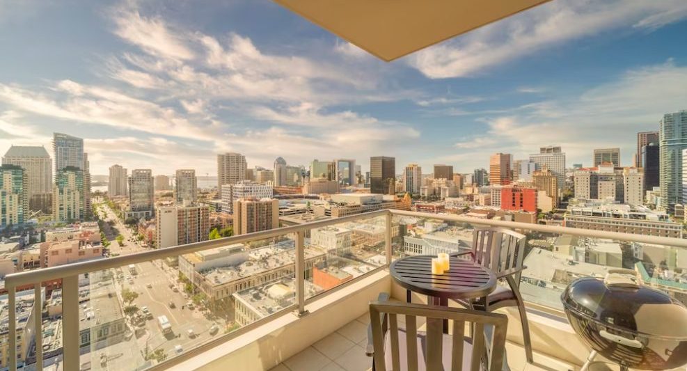 Outdoor patio with small dining table and grill overlooking downtown San Diego skyline on sunny day. San Diego beach vacation.