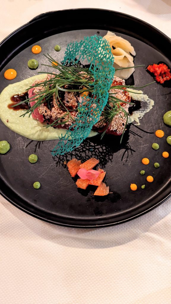 Tuna crudo beautifully decorated on black plate