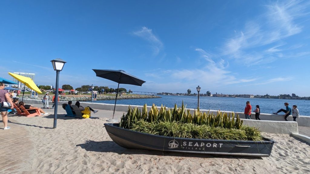 Small wood boat on sand decorated with plants along the San Diego Bay at Seaport Village