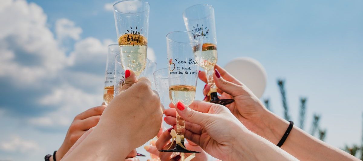 Close up of champagne toast, champagne glasses read "team bride" on sunny day. San Diego bachelorette party.