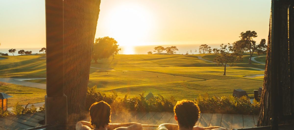 Couple in outdoor jacuzzi watching sunset over golf course and ocean in the distance. The Lodge at Torrey Pines Best hotels in San Diego for Couples