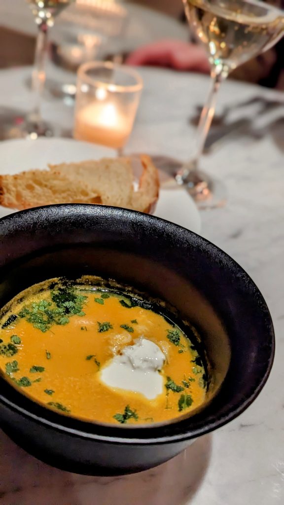 Blue Crab Bisque with cream and a crusty slice of bread