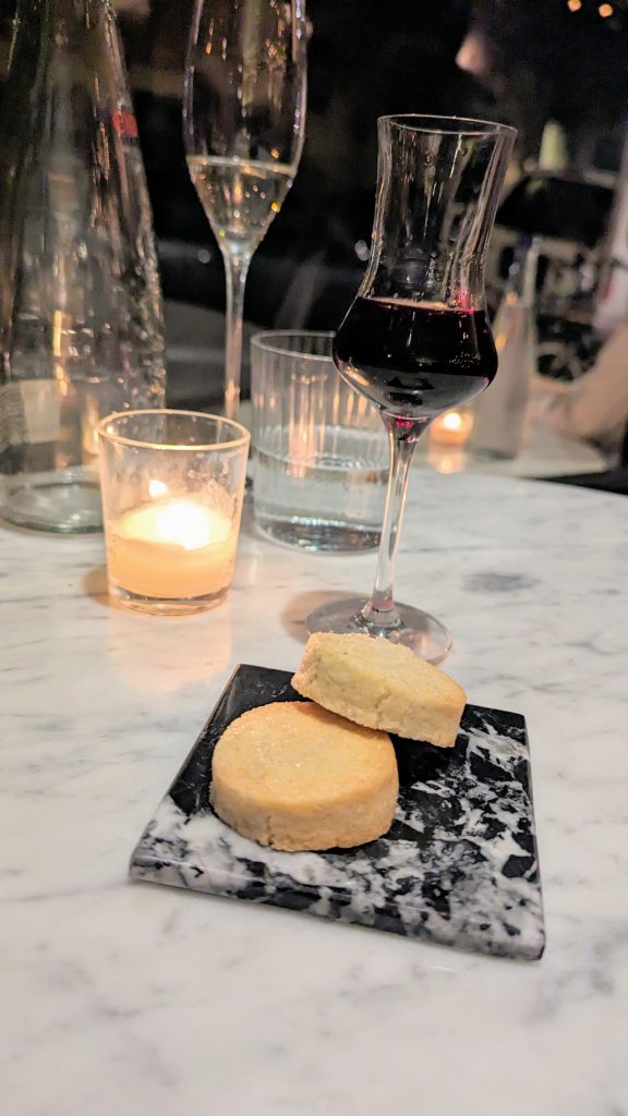 two cookies on a black coaster with glasses and candles in the background