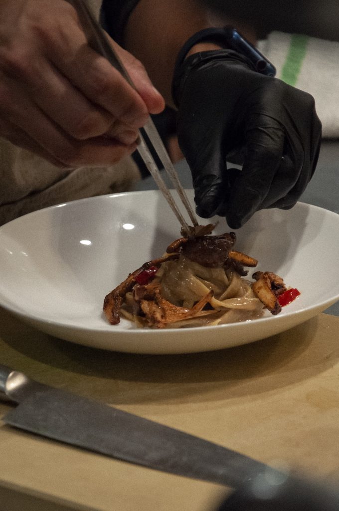 chef hands plating procini linguini 