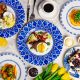 Decadent brunch spread on colorful blue plates with yellow tulips, coffee, and mimosas. San Diego Easter Brunch, Herb & Wood.