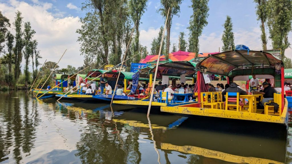 Colorful wooden boats on Heron sitting by the banks of the canals at Xochimilco