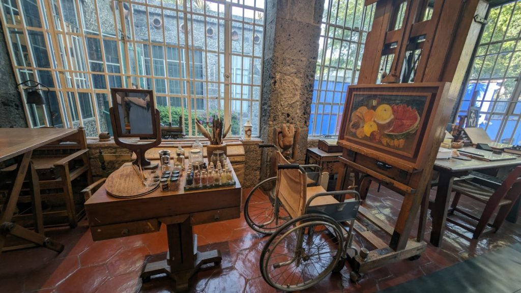 Frida Kahlo’s art studio with canvas, table with paints and her wheelchair